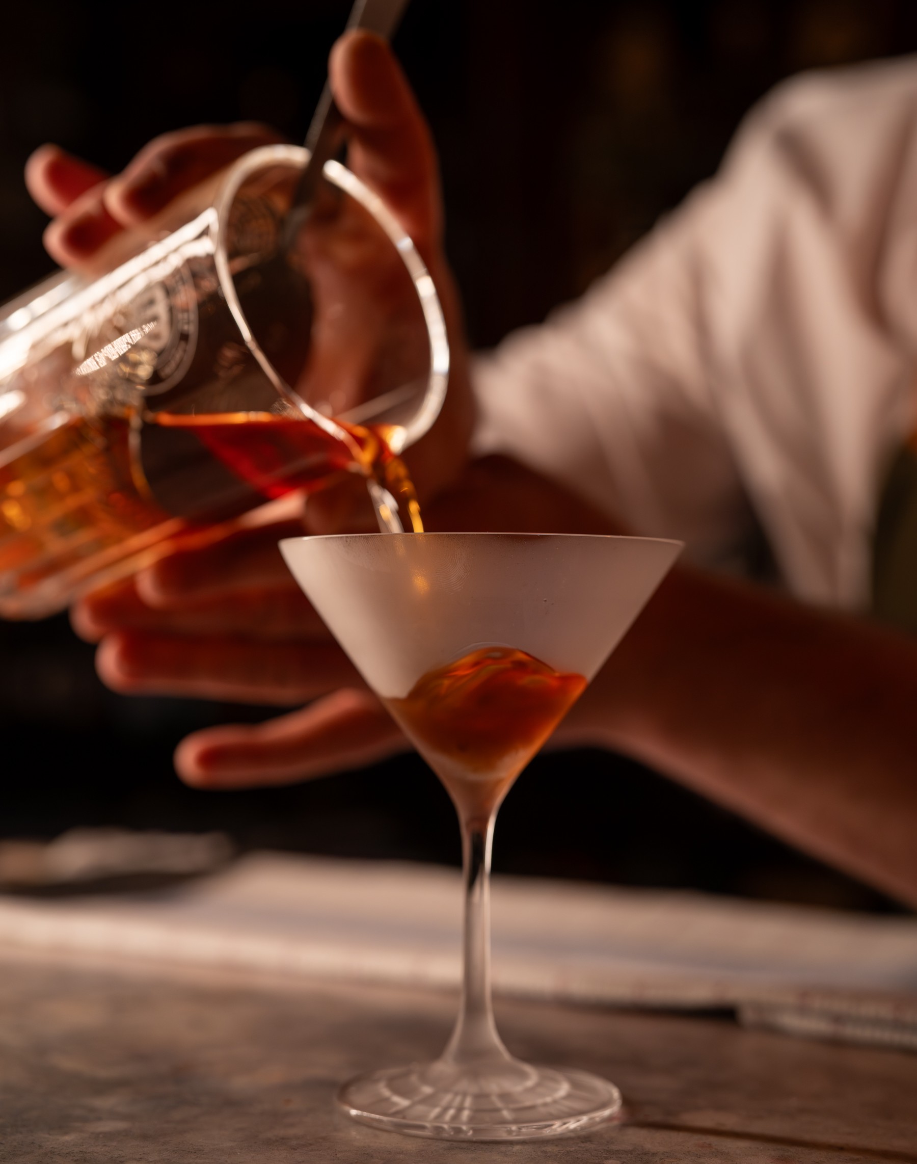 A VCC bartender carefully pouring a cocktail