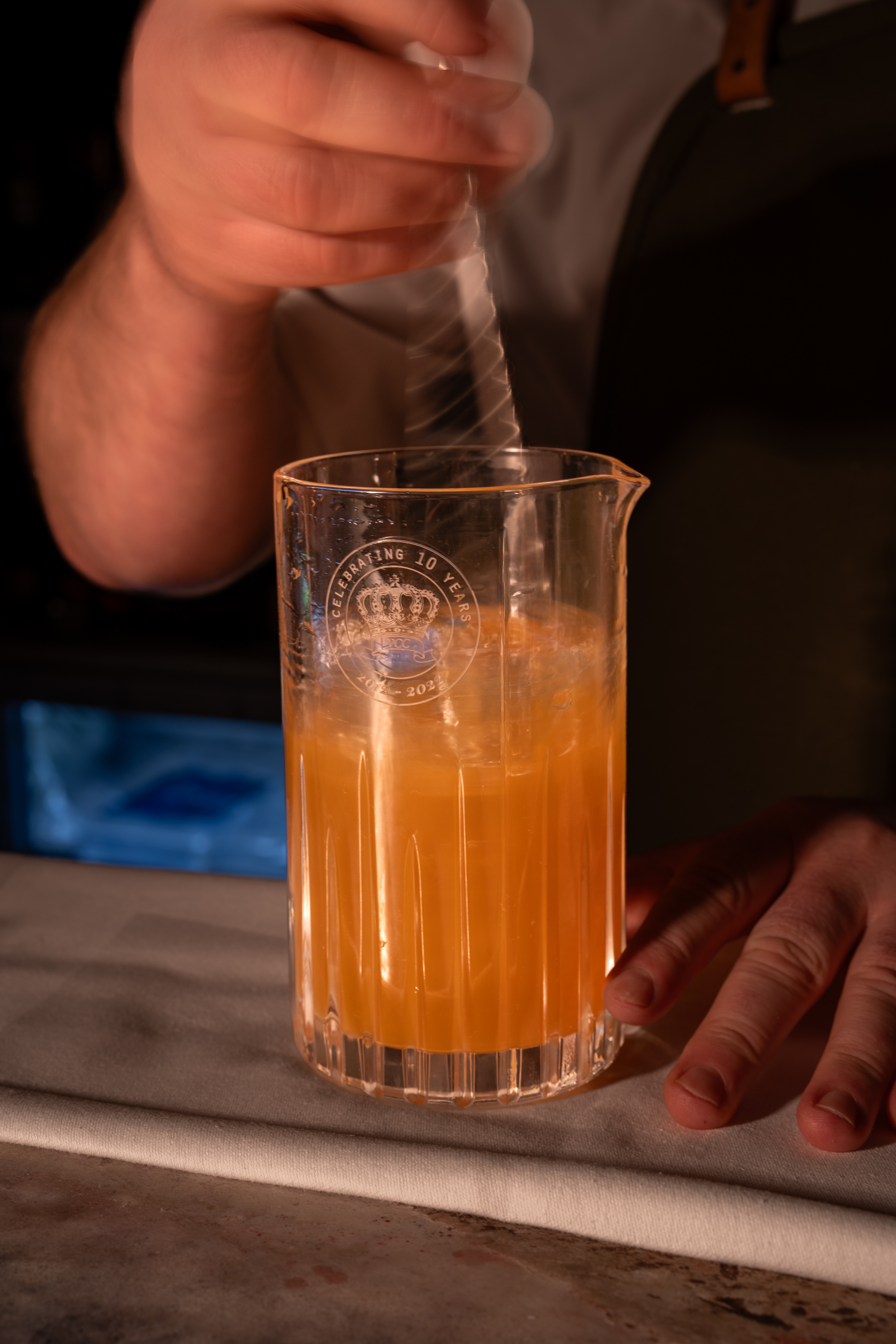 A bartender working with a cocktail mixing glass